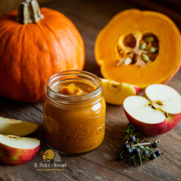 Vasetto di salsa di zucca e mele cotogne al ginepro con ingredienti freschi.