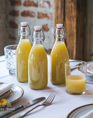 Bottiglia di succo di mele cotogne su tavola apparecchiata, con bicchiere di succo accanto.