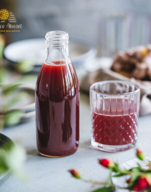 Bottiglia di succo di rosa canina su tavola apparecchiata, con bicchiere di succo accanto.